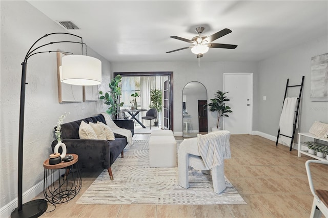 living room with tile patterned flooring, baseboards, visible vents, and a ceiling fan