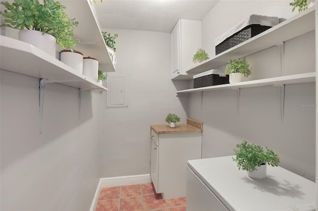 clothes washing area featuring light tile patterned flooring and baseboards