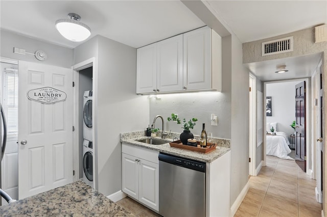 kitchen featuring stacked washer / dryer, a sink, visible vents, white cabinetry, and dishwasher