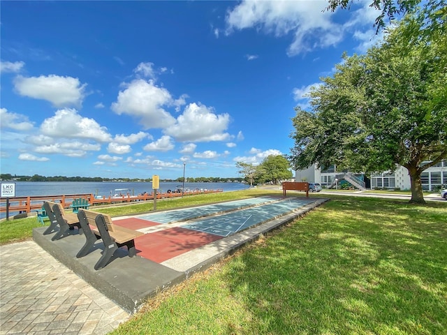 view of community featuring a water view, a lawn, and shuffleboard