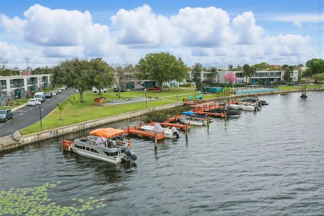 view of dock with a water view, boat lift, and a yard