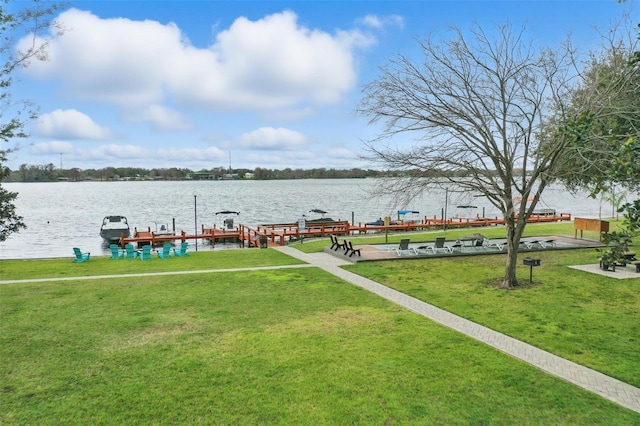 view of dock with a water view, boat lift, and a lawn