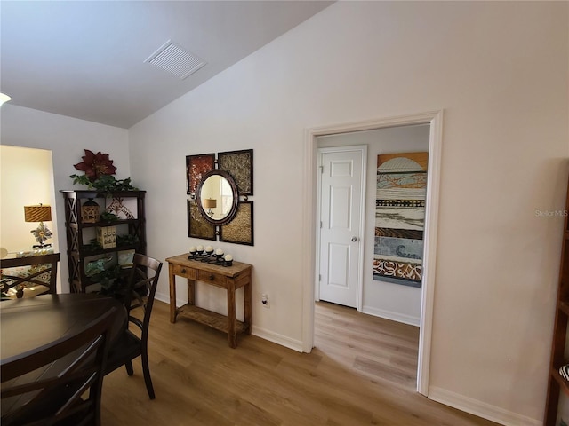 interior space featuring lofted ceiling, baseboards, visible vents, and wood finished floors