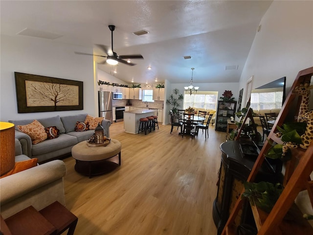 living room featuring visible vents, light wood finished floors, and ceiling fan with notable chandelier