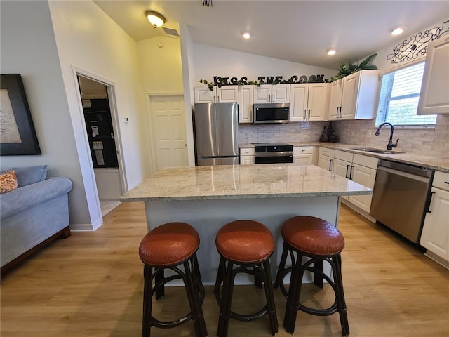 kitchen with appliances with stainless steel finishes, a center island, white cabinetry, and a sink