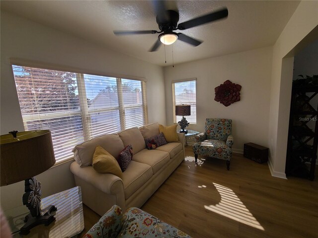 living room with ceiling fan, baseboards, and wood finished floors