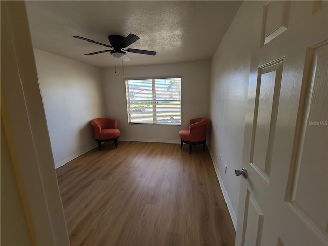 unfurnished room featuring a textured ceiling, ceiling fan, light wood finished floors, and baseboards