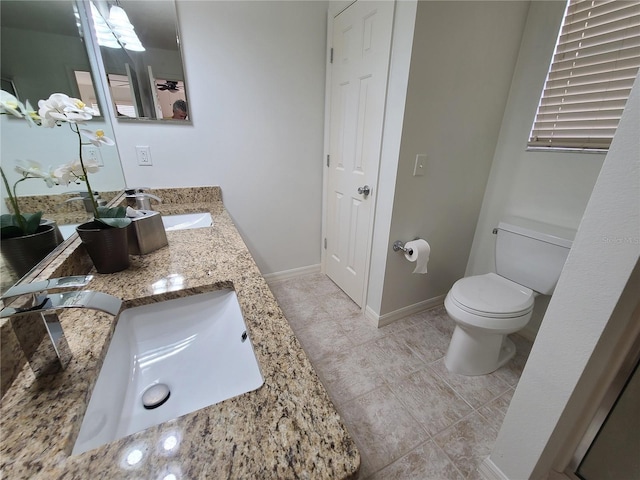 bathroom with toilet, a sink, baseboards, a closet, and double vanity