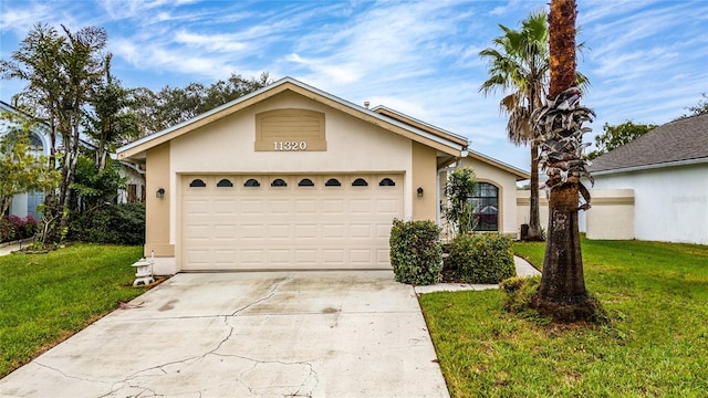 view of front of home featuring driveway, a garage, a front lawn, and stucco siding