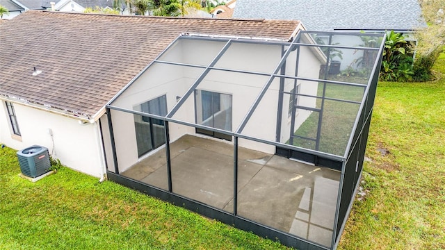 back of property with a patio, central AC unit, a lanai, roof with shingles, and a lawn