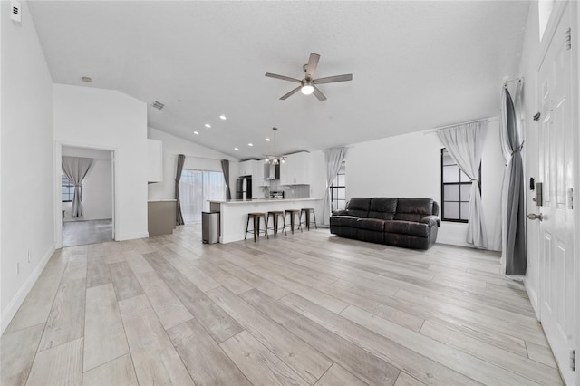 living room with recessed lighting, visible vents, light wood-style flooring, a ceiling fan, and vaulted ceiling