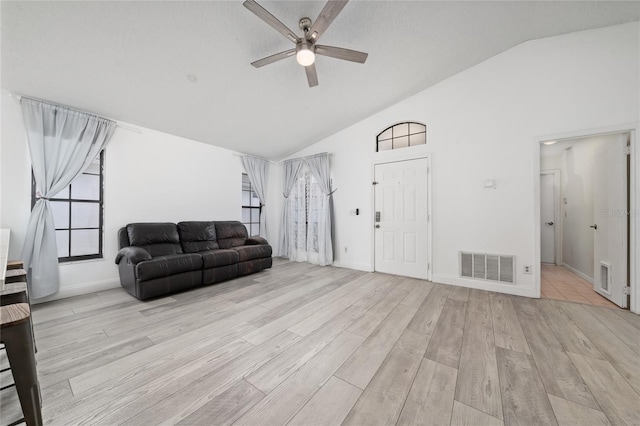 living area featuring a ceiling fan, visible vents, vaulted ceiling, and light wood-style flooring