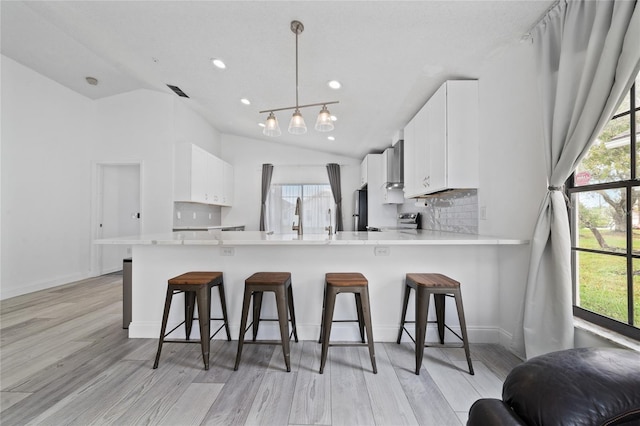 kitchen with a peninsula, white cabinetry, hanging light fixtures, light countertops, and range