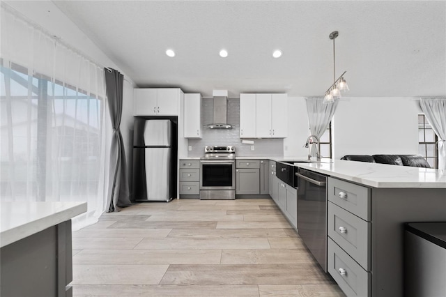 kitchen with stainless steel appliances, white cabinets, gray cabinets, wall chimney exhaust hood, and pendant lighting