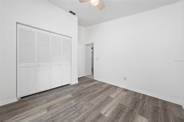 unfurnished bedroom featuring a closet, visible vents, a ceiling fan, wood finished floors, and baseboards