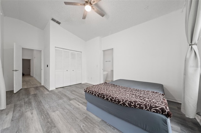 bedroom with lofted ceiling, light wood-style flooring, visible vents, and a closet