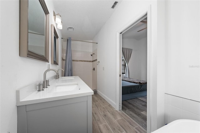 ensuite bathroom with visible vents, ensuite bath, a tile shower, wood finish floors, and a sink