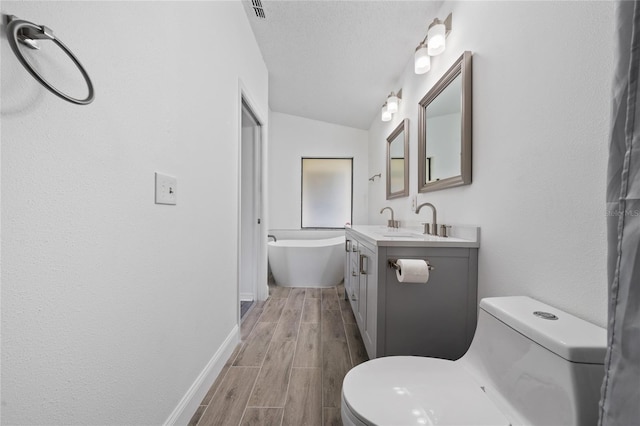 bathroom featuring a soaking tub, toilet, wood tiled floor, vanity, and a textured ceiling