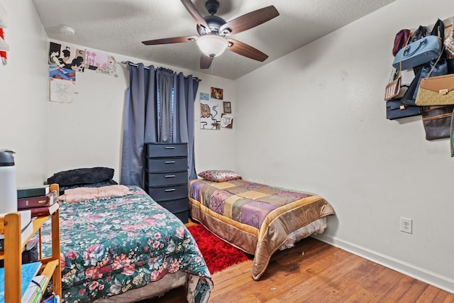 bedroom featuring a textured ceiling, ceiling fan, wood finished floors, and baseboards