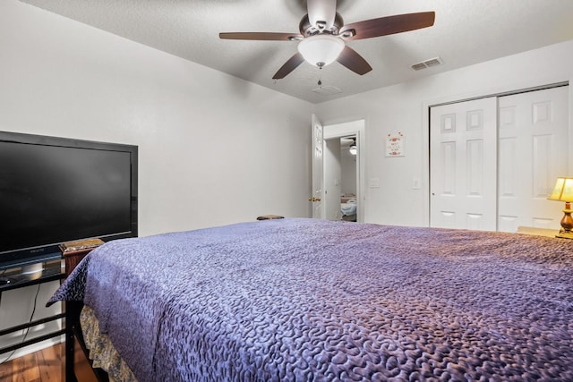 bedroom with a closet, visible vents, ceiling fan, a textured ceiling, and wood finished floors