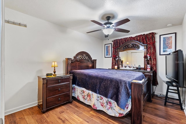 bedroom featuring ceiling fan, a textured ceiling, baseboards, and wood finished floors