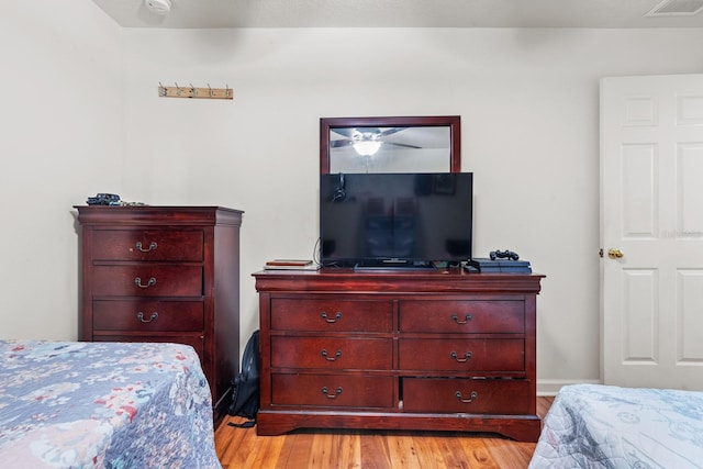 bedroom with baseboards, visible vents, and light wood finished floors