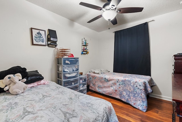 bedroom featuring ceiling fan, a textured ceiling, baseboards, and wood finished floors