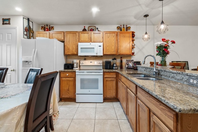 kitchen featuring hanging light fixtures, white appliances, light stone counters, and a sink