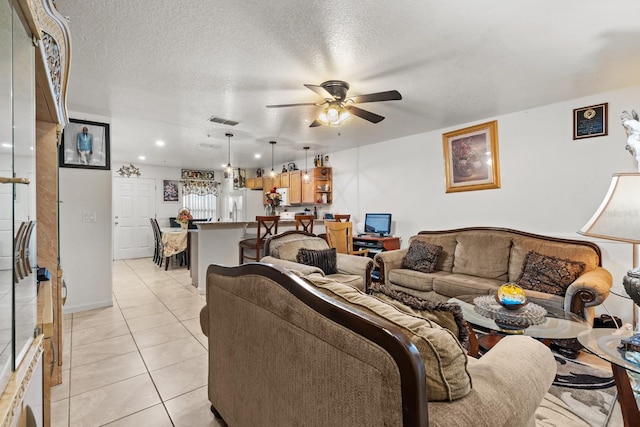 living room with a textured ceiling, visible vents, a ceiling fan, and light tile patterned flooring