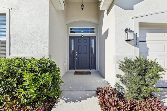 entrance to property with an attached garage and stucco siding