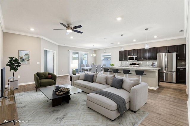 living room featuring light wood-style floors, visible vents, crown molding, and baseboards