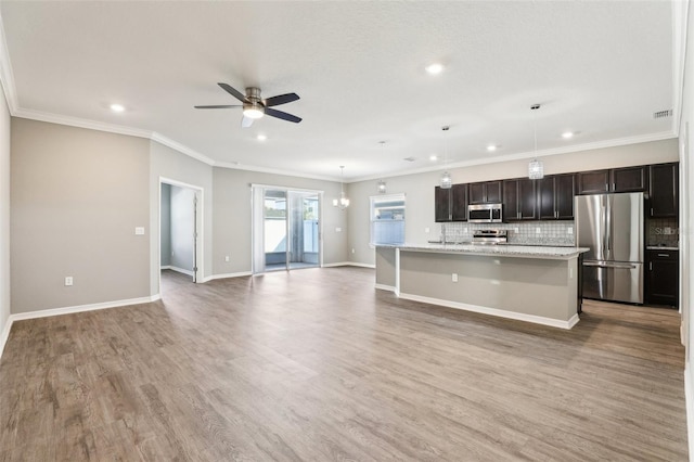 kitchen featuring appliances with stainless steel finishes, a breakfast bar, open floor plan, a kitchen island with sink, and light wood-type flooring