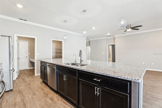 kitchen featuring decorative light fixtures, stainless steel appliances, a sink, visible vents, and a center island with sink