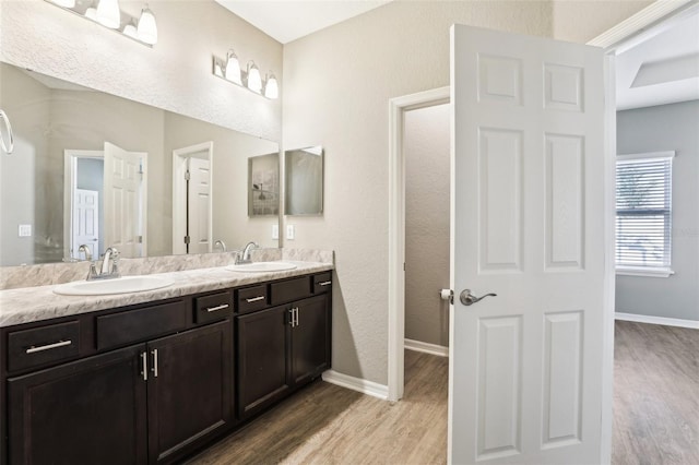 full bath featuring a sink, baseboards, and wood finished floors