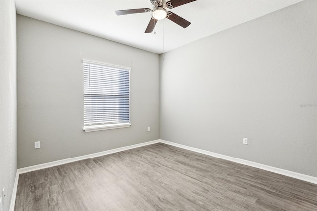 empty room featuring a ceiling fan, baseboards, and wood finished floors