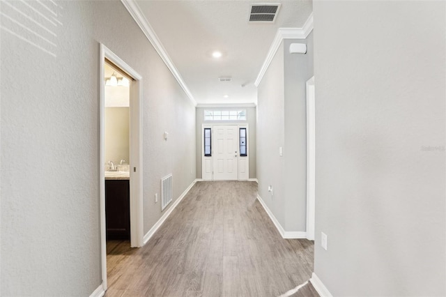 interior space featuring crown molding, baseboards, visible vents, and light wood-style floors