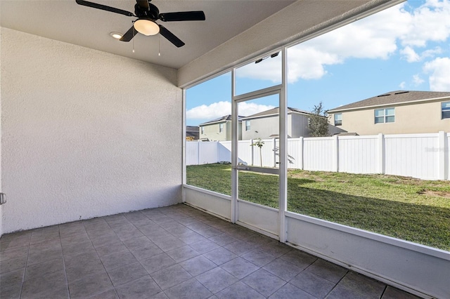 unfurnished sunroom featuring a residential view, plenty of natural light, and ceiling fan