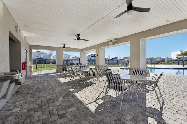 view of patio / terrace with ceiling fan, outdoor dining area, a community pool, a water view, and fence