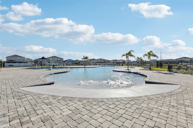 community pool featuring a patio, fence, and a residential view