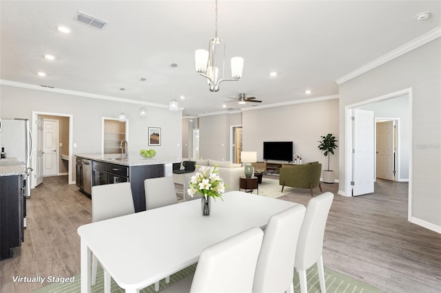 411 Lily Ln, Davenport, FL 33837 - dining room with a ceiling fan, recessed lighting, crown molding, light wood finished floors, and a chandelier