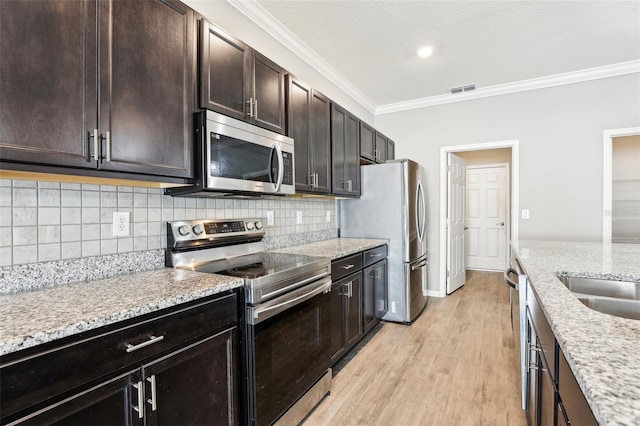 411 Lily Ln, Davenport, FL 33837 - kitchen featuring appliances with stainless steel finishes, ornamental molding, tasteful backsplash, light wood-style floors, and light stone counters