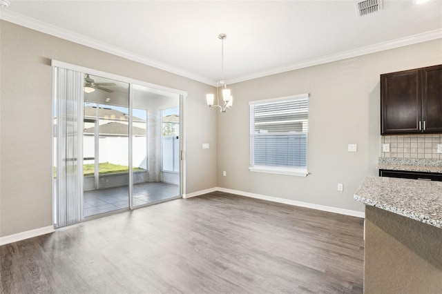 411 Lily Ln, Davenport, FL 33837 - unfurnished dining area with dark wood-type flooring, ornamental molding, a chandelier, and a ceiling fan