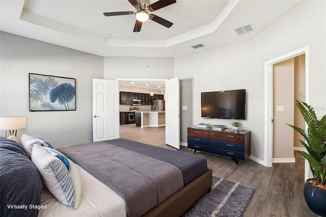 411 Lily Ln, Davenport, FL 33837 - bedroom with a tray ceiling, freestanding refrigerator, wood finished floors, and a ceiling fan