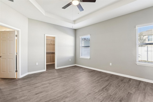 411 Lily Ln, Davenport, FL 33837 - unfurnished bedroom with a tray ceiling, wood finished floors, a spacious closet, and a closet