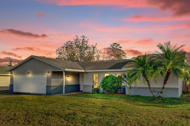 ranch-style house with driveway, brick siding, an attached garage, a front lawn, and stucco siding