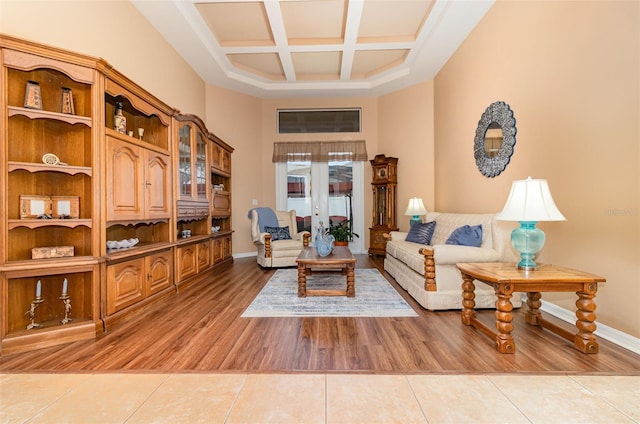 interior space featuring a towering ceiling, light tile patterned flooring, coffered ceiling, beamed ceiling, and baseboards