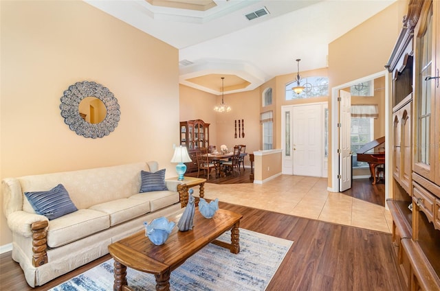 living area featuring a high ceiling, visible vents, baseboards, and wood finished floors