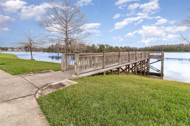 view of dock with a water view and a yard