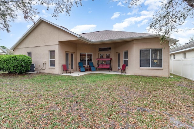 rear view of property with stucco siding, a yard, fence, and a patio