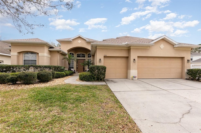 view of front of house featuring an attached garage, driveway, a front lawn, and stucco siding